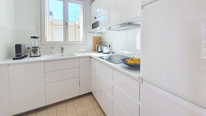 Eine kleine Küche mit weißen Schränken, einer eingebauten Mikrowelle und einem Fenster über der Spüle.