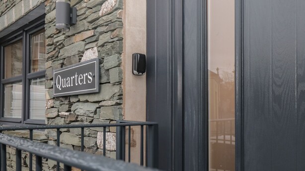 A stone building with a sign reading "Quarters" and a black door. - Quarters (Ambleside)