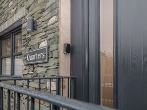 A stone building with a sign reading "Quarters" and a black door. - Quarters (Ambleside)