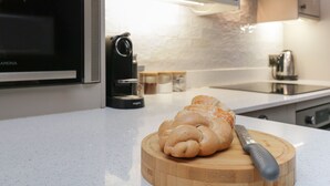A kitchen with a wooden cutting board, a loaf of bread, and a coffee maker. - Quarters (Ambleside)