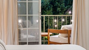 A bedroom with a large window, a wooden chair, and a bed.