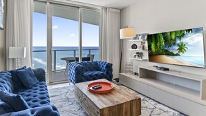 A modern living room with a large TV, a blue sofa, and a wooden coffee table. - Wonderfull Condo by the Sea in Hollywood Beach (Hollywood)
