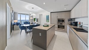 A modern kitchen with a central island, built-in appliances, and a dining area with blue chairs. - Wonderfull Condo by the Sea in Hollywood Beach (Hollywood)