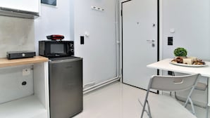 A compact kitchen with a microwave, refrigerator, and a small coffee machine on a wooden countertop. - Unique Lodging (Athens)