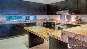 A modern kitchen with dark cabinetry, a granite countertop, and stainless steel appliances.