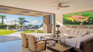 A modern living room with a glass coffee table, leather sofas, and a large painting of a shark.