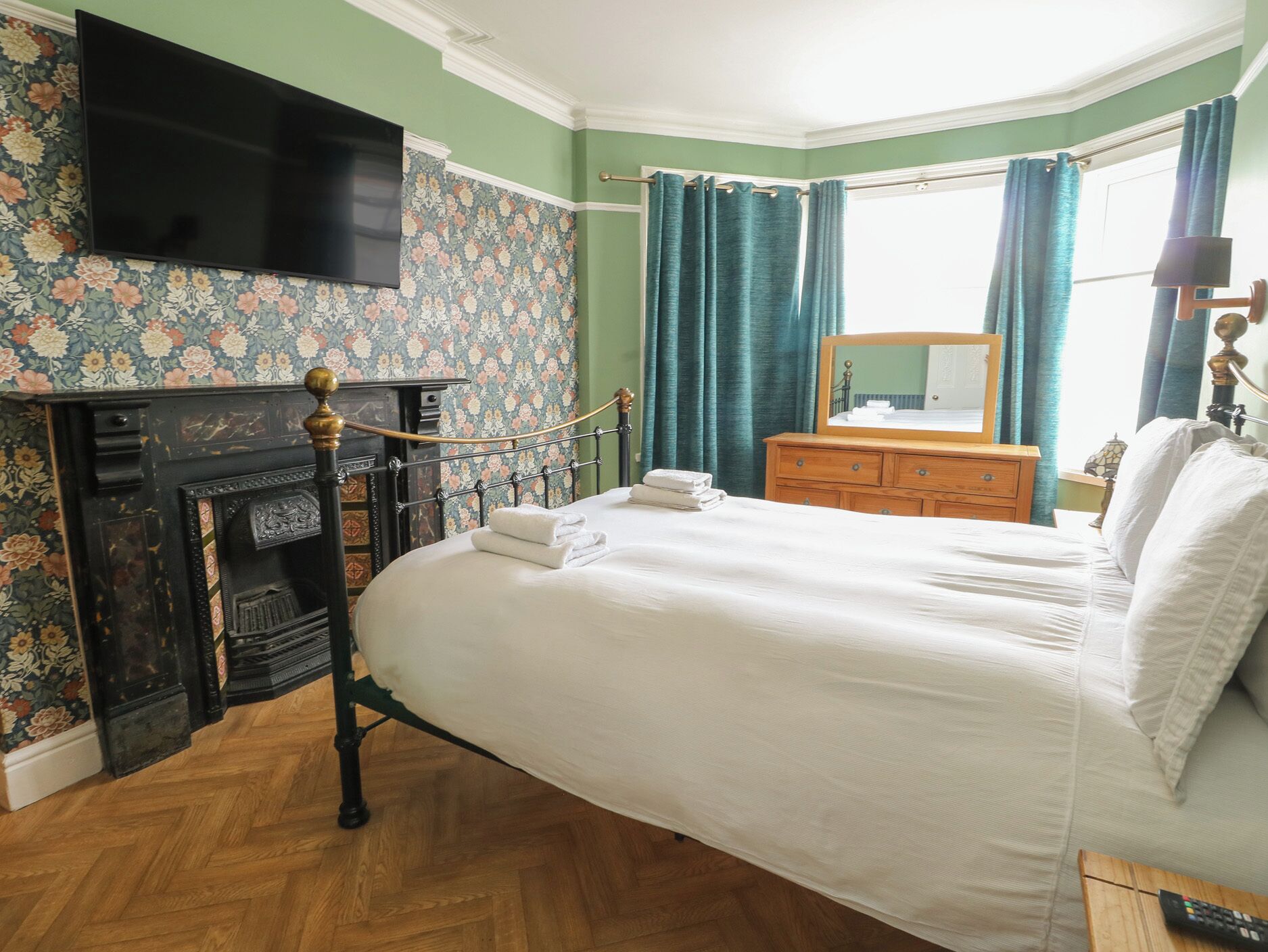 Un dormitorio con cama, chimenea, cómoda, espejo y televisor.
