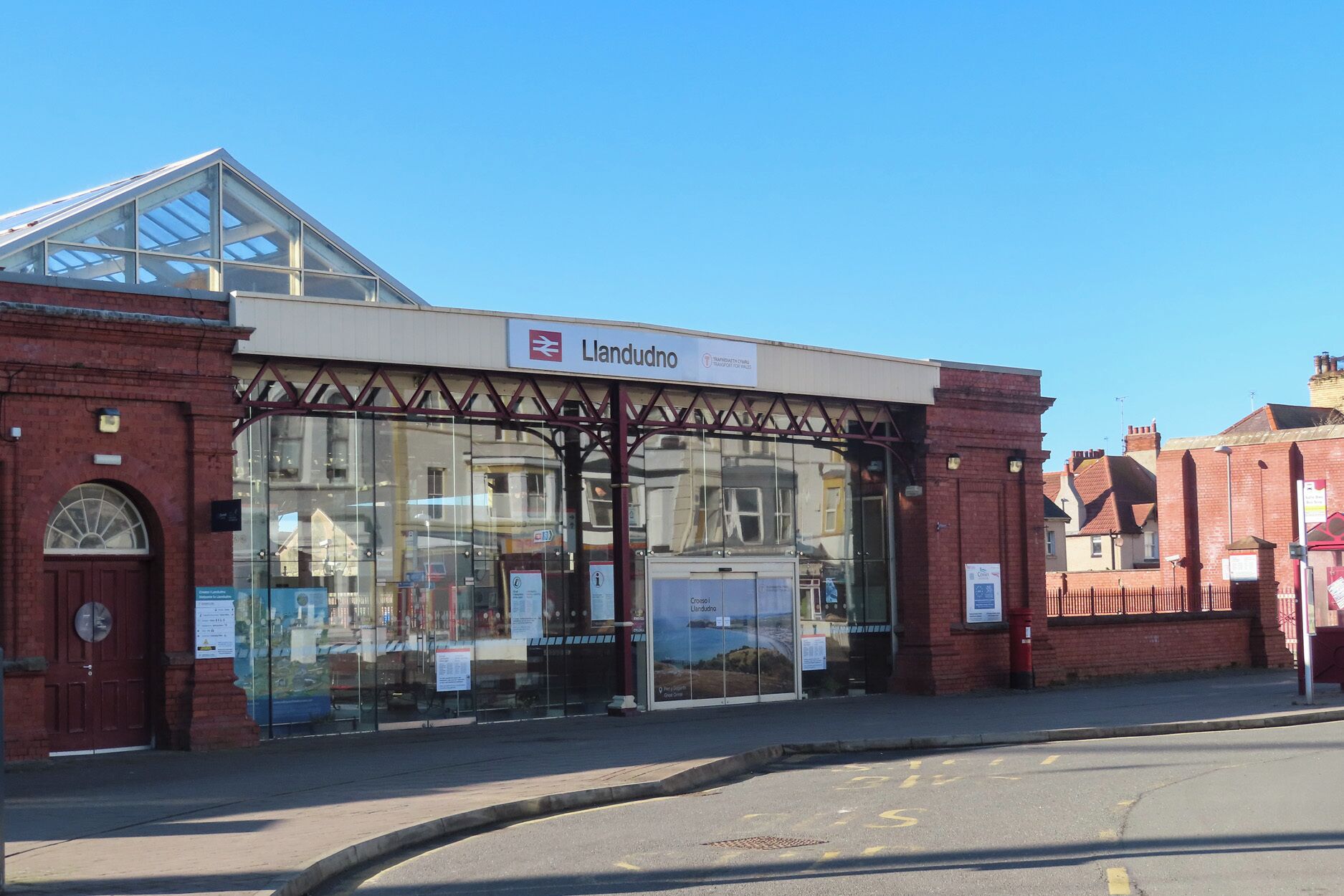 A train station with a glass canopy and a sign reading "Landudno".