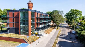 Een modern gebouw met een bakstenen gevel en grote ramen, met een klein torentje en een overdekte gang.