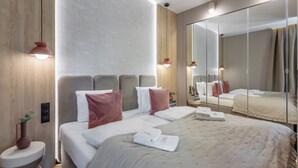 Een moderne hotelkamer met een groot bed, een nachtkastje, een spiegel en een wandlamp.