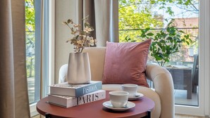 Een gezellige kamer met een ronde tafel, een vaas met bloemen en boeken getiteld 'The Fashion Paris'.