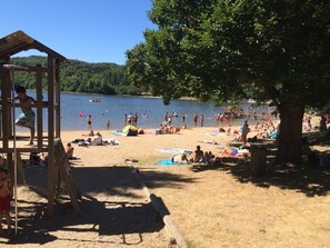 A beach with a wooden structure, people relaxing, and a lake in the background. - " LA Cabane " (Mazamet)
