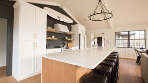 Une cuisine moderne avec des meubles blancs, un grand îlot central et un lustre.