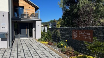 Un edificio moderno con balcón, entrada protegida por un portón y un cartel que dice 'Red Fox Partnagy'.