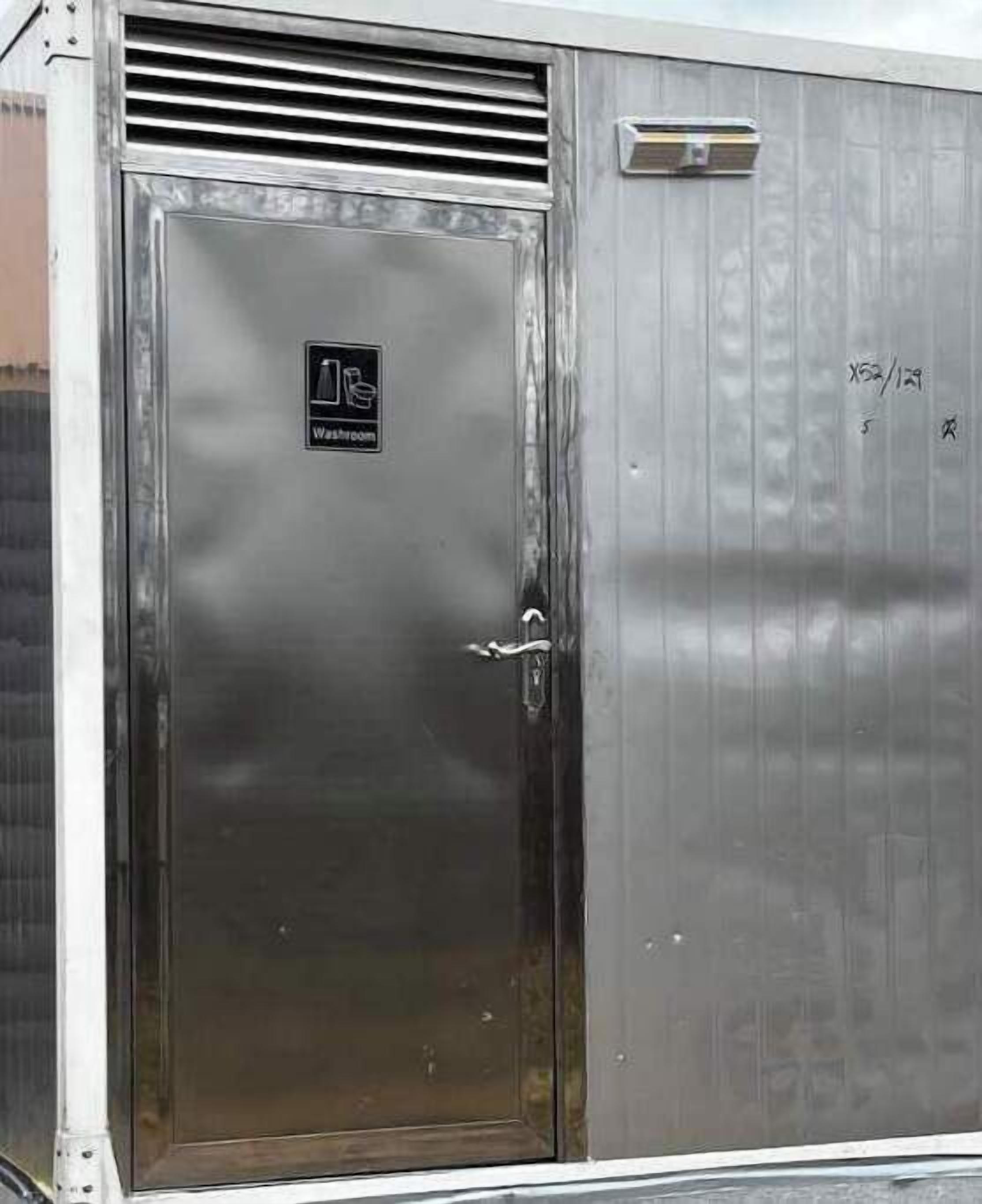 A metallic door with a 'Washing Machine' sign, a vent above it, and a small window with handwritten text.