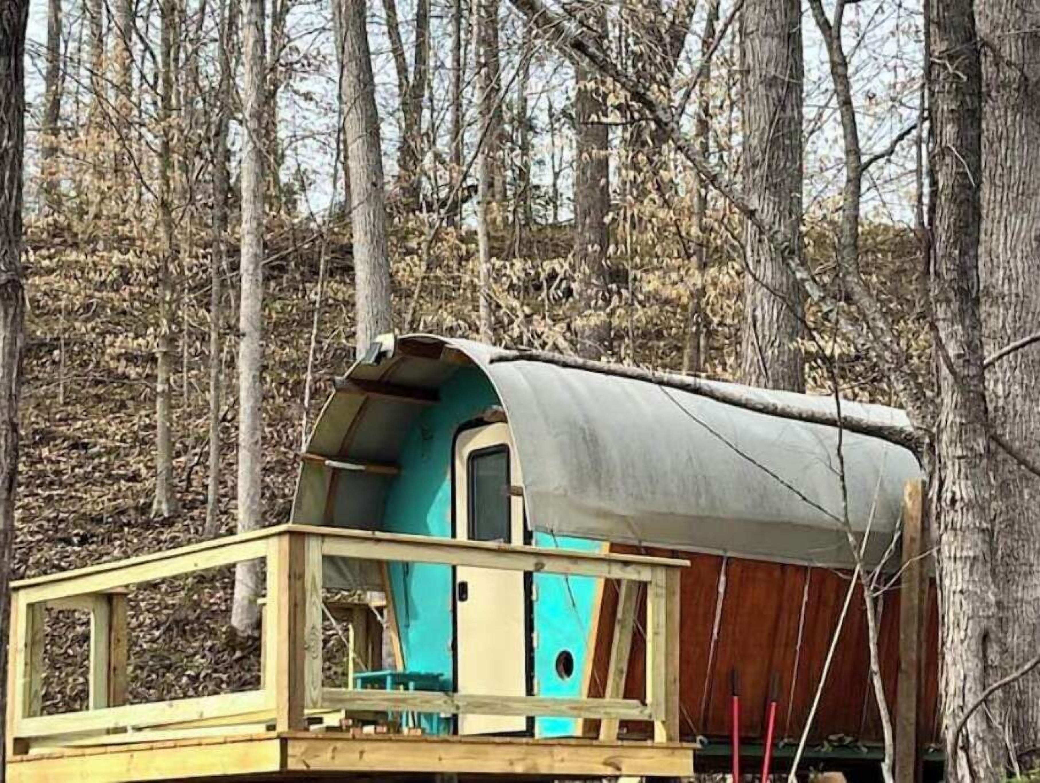 Una piccola costruzione in legno con una porta e una finestra, circondata da alberi.