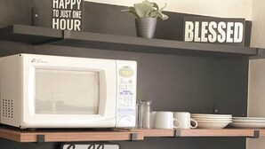 A kitchen area with a microwave, a coffee bar sign, and a shelf with a plant and mugs. - Departamento Cerca de Mall y D1.facturamos! (Chihuahua)