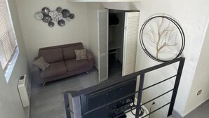 A room with a brown sofa, a wall-mounted clock, and a circular decorative item. - Departamento Cerca de Mall y D1.facturamos! (Chihuahua)