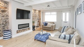 A living room with a fireplace, a sofa, a coffee table, and a television. - Ty Bara (Cemaes Bay)