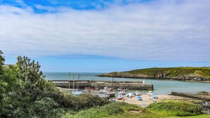 A coastal marina with boats docked, a sandy beach, and a rocky coastline. - Ty Bara (Cemaes Bay)