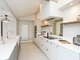 Una cocina moderna con armarios blancos, horno empotrado, placa de cocina y tostadora.