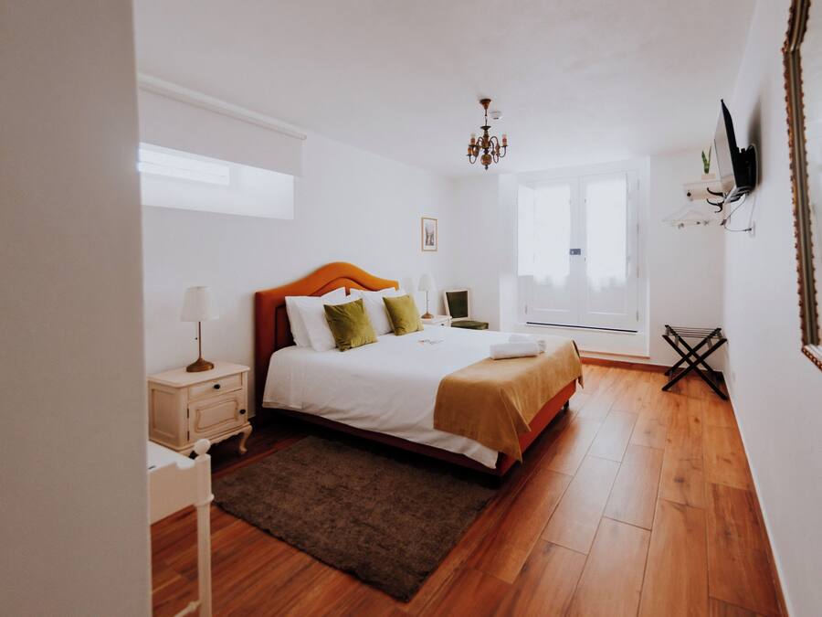 A bedroom with a bed, bedside table, lamp, and a mirror.