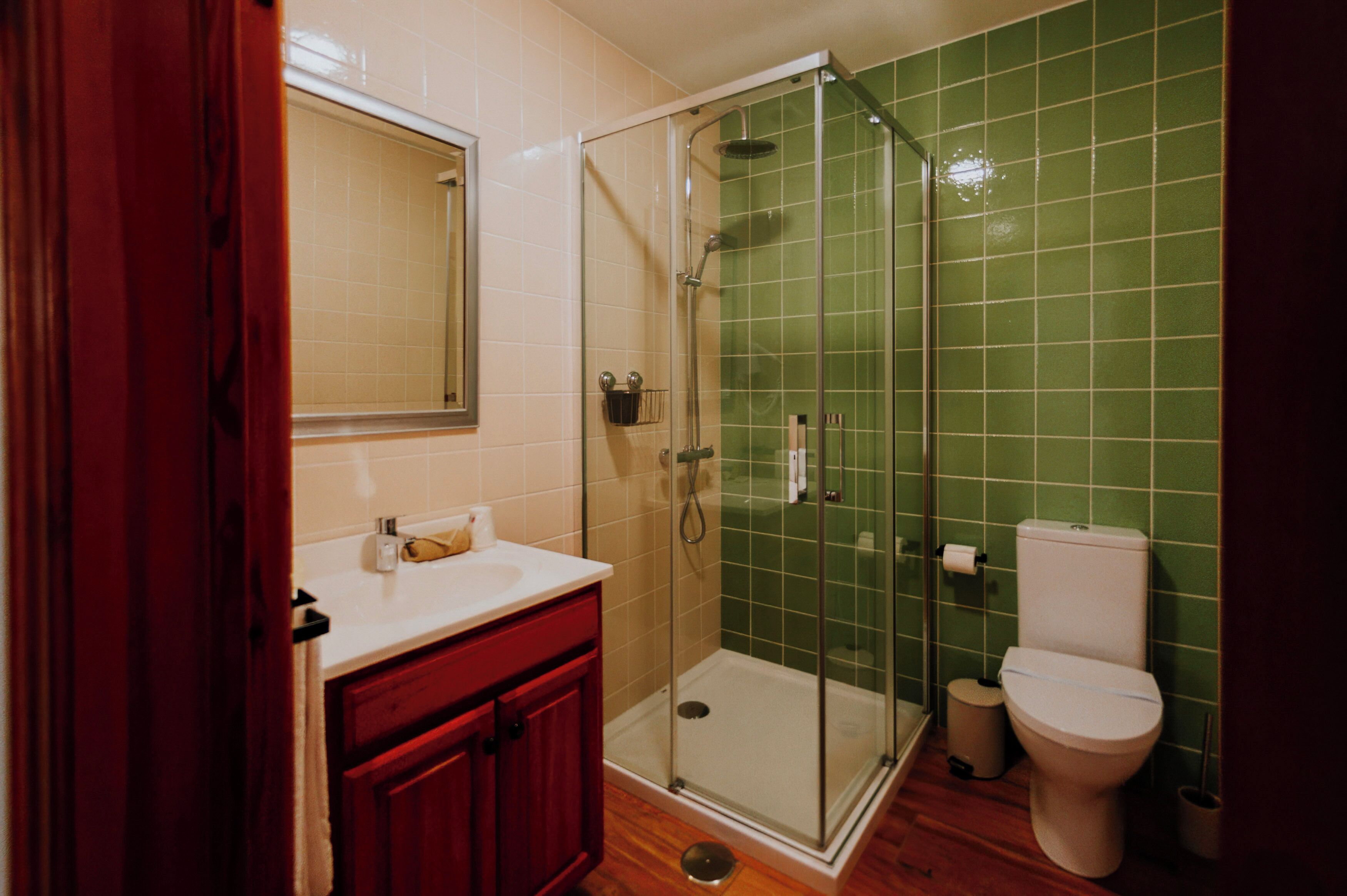 Ein Badezimmer mit Duschkabine aus Glas, Toilette und Waschbecken mit Spiegel darüber.