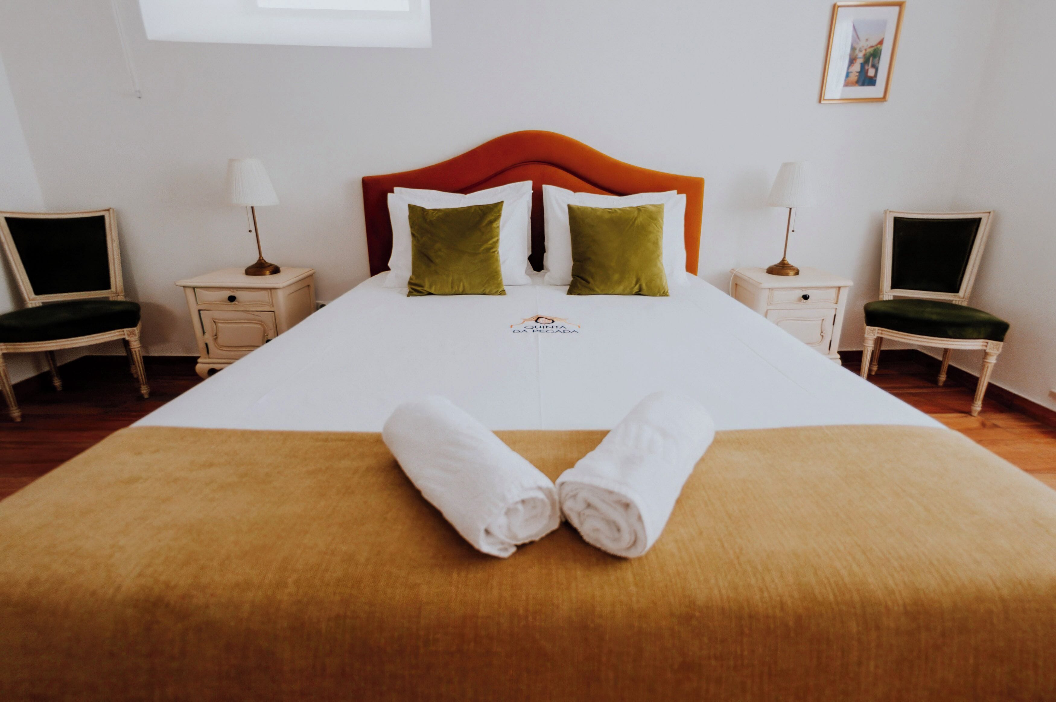 Ein Hotelzimmer mit einem großen Bett, zwei Nachttischen, zwei Stühlen und einem gerahmten Bild an der Wand.