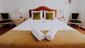 Ein Hotelzimmer mit einem großen Bett, zwei Nachttischen, zwei Stühlen und einem gerahmten Bild an der Wand.