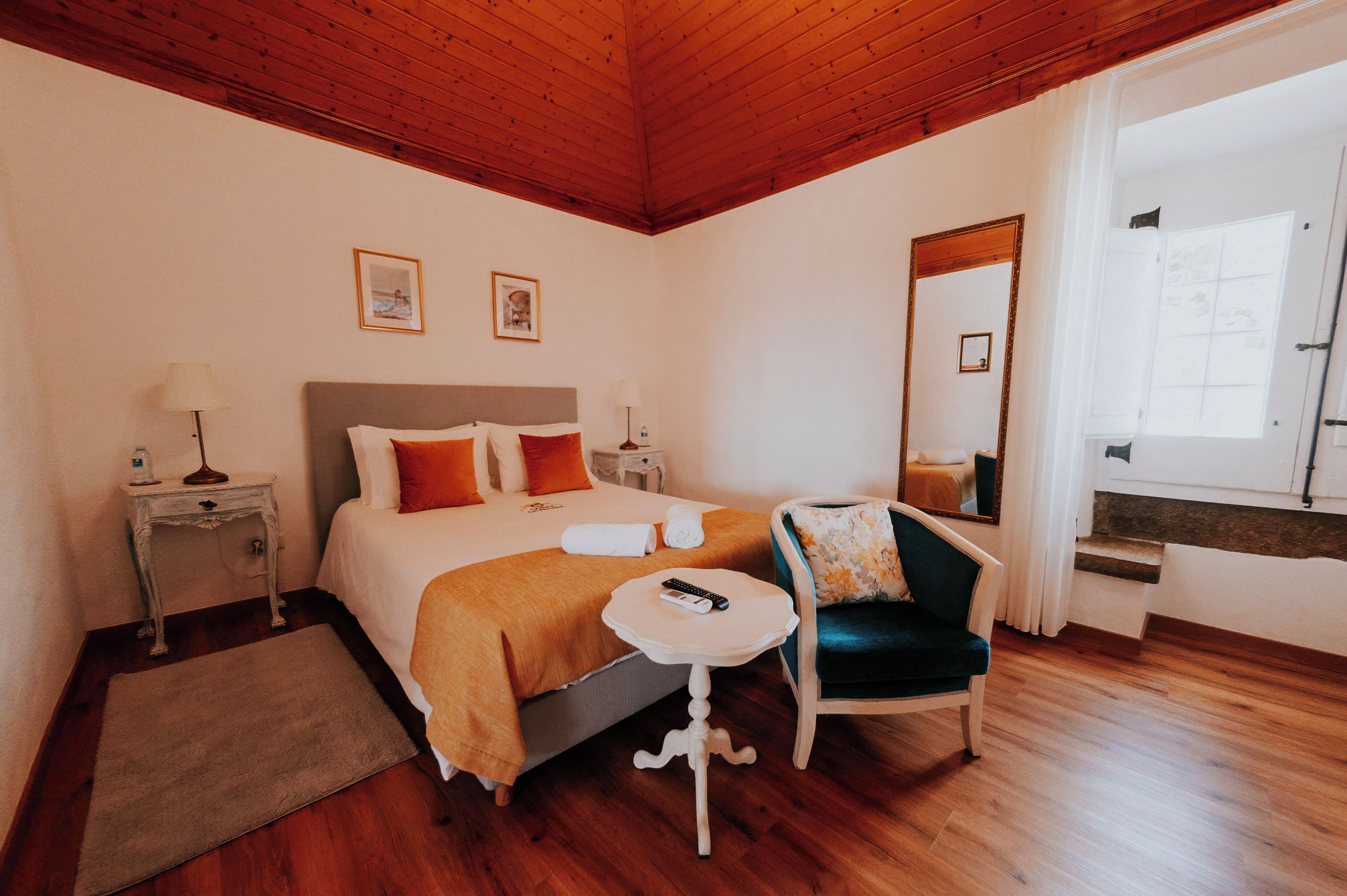 Una habitación de hotel con una cama, una silla, una mesita y un espejo.