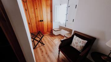 A wooden floor, a chair with a floral pillow, a small table, and a wall-mounted lamp.