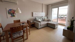 A modern living room with a dining area, a sofa, and a view of the outside.