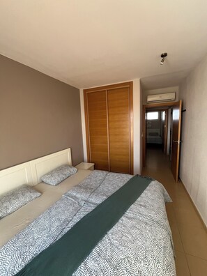 Un dormitorio con cama, armario y aire acondicionado.
