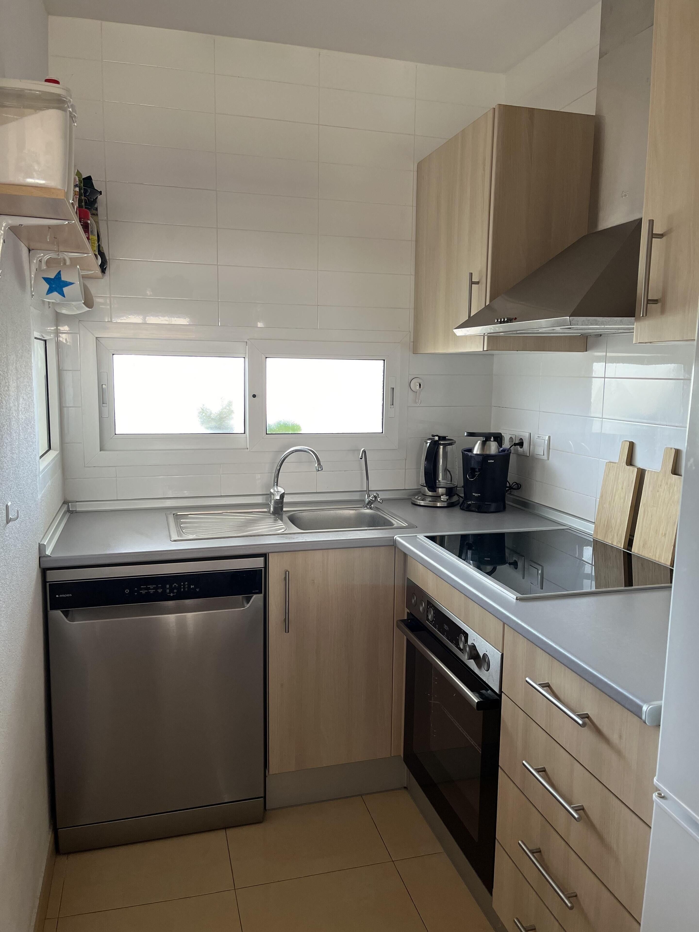 Una cocina moderna con electrodomésticos de acero inoxidable, armarios de madera y un ventanal que proporciona luz natural.