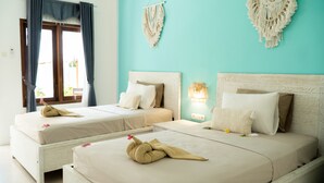 Ein Hotelzimmer mit zwei Betten, einem Fenster mit Vorhängen und Makramee-Wanddekoration.