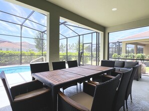 An outdoor patio with a pool, large windows, and wicker furniture. - Topical Style! Relax By the Pool & Create Family Memories! Resort Near Disney! (Davenport)
