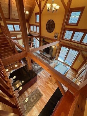 Ein mehrstöckiger Innenraum aus Holz mit Kamin, großen Fenstern und einer Treppe.