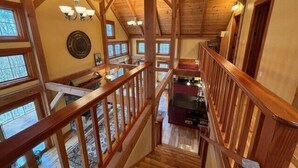 A wooden interior with a staircase, wooden beams, and a view of the outside.