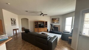 A living room with a black sofa, a TV, and a fireplace. - Cozy 4-bedroom house in delightful San Antonio with AC, WiFi (San Antonio)