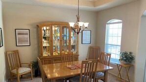 A dining room with a wooden table and chairs, a glass-fronted china cabinet, and a chandelier. - Cozy 4-bedroom house in delightful San Antonio with AC, WiFi (San Antonio)