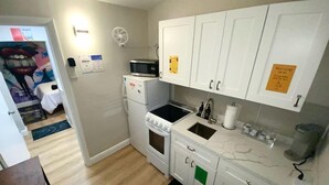 A compact kitchen with white cabinets, a microwave, a stove, and a sink.