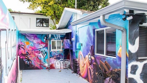 A colorful exterior with vibrant graffiti art, a small window, and a door.