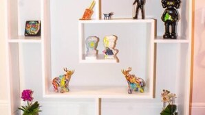 A white, multi-tiered display shelf with various decorative items including figurines, a pineapple, and small plants. - Unique Miami Art Escape w/ HotTub, Arcade & Murals (Miami)