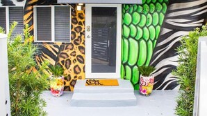 A house with a zebra-striped exterior wall, a door with a glass panel, and a small porch area with potted plants. - Unique Miami Art Escape w/ HotTub, Arcade & Murals (Miami)
