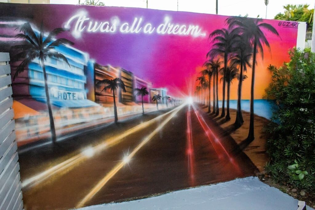 A mural with a road leading to a hotel, palm trees, and the text "It was all a dream."