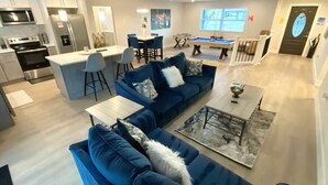 En moderne stue med en blå sofa, et sofabord og et billardbord.