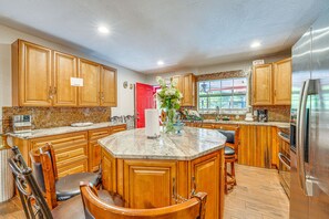 Una cucina con mobili in legno, un piano di lavoro in marmo e un frigorifero in acciaio inossidabile.