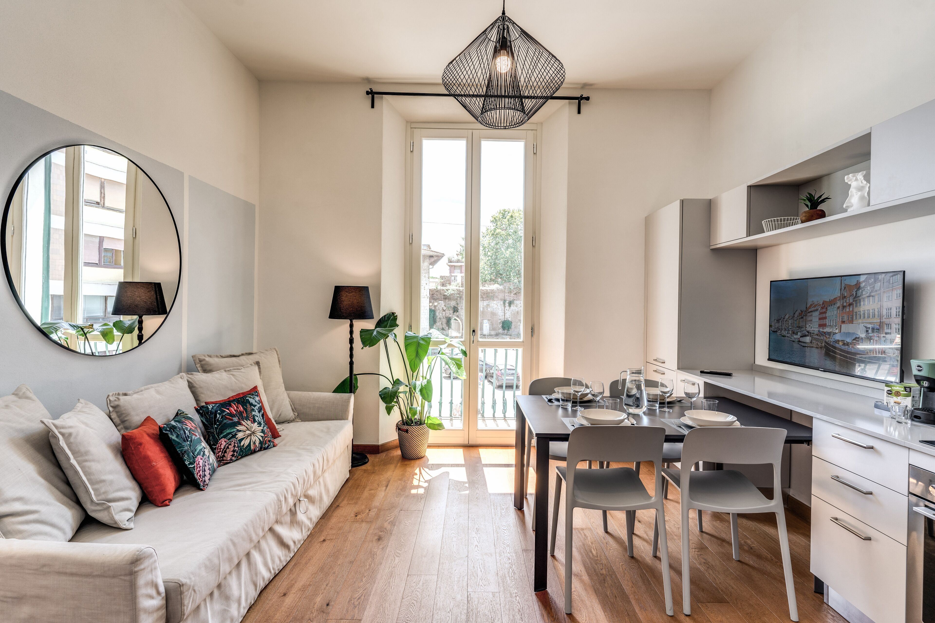A modern apartment with a dining area, kitchen, and a large window.