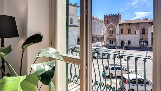 A view from a window overlooking a street with parked cars and historic buildings. - AwesHome Luxury Apartment (Pisa)