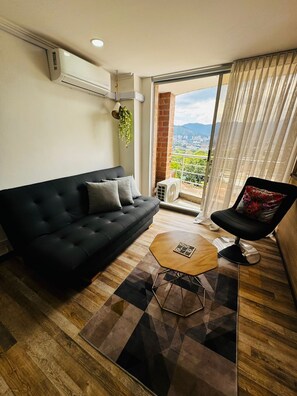 Een moderne woonkamer met een zwarte bank, een houten salontafel en een zwarte stoel.